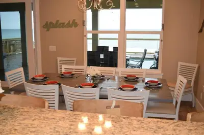 a dining room with a table and chairs and the ocean at The Lighthouse 6 Bd Home With Beachfront Pool And Hot Tub in Panama City Beach