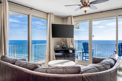 a living room with a large couch and a view of the ocean at Shores Of Panama Best 3 Bedroom With Wrap-Around Balcony! in Panama City Beach