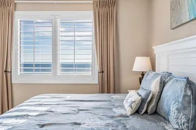 a bedroom with a bed and a window with the ocean at Shores Of Panama Best 3 Bedroom With Wrap-Around Balcony! in Panama City Beach