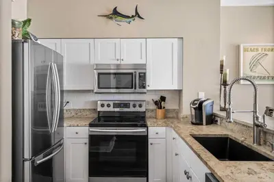a kitchen with a stainless steel refrigerator and a stove at Shores Of Panama Best 3 Bedroom With Wrap-Around Balcony! in Panama City Beach