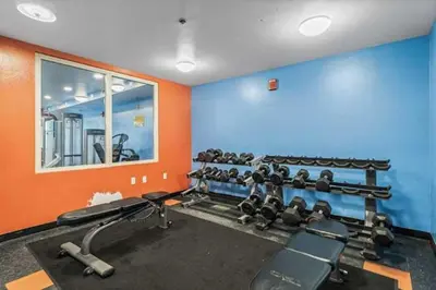 a gym with blue and orange walls and rows of equipment at Shores Of Panama Best 3 Bedroom With Wrap-Around Balcony! in Panama City Beach