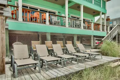 a group of chairs sitting on a deck in front of a house at Beachcomber - Beachfront With Pool And Hot Tub - On The Beach! in Panama City Beach
