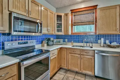 a kitchen with wooden cabinets and stainless steel appliances at Beachcomber - Beachfront With Pool And Hot Tub - On The Beach! in Panama City Beach