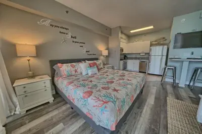 a large bedroom with a bed and a kitchen at Deluxe Beachfront Studio, Shores of Panama, Oceanviews and Updated in Panama City Beach