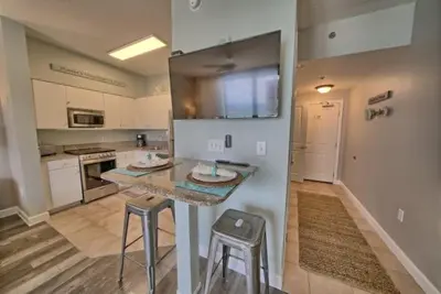 a large kitchen with a counter and stools in it at Deluxe Beachfront Studio, Shores of Panama, Oceanviews and Updated in Panama City Beach