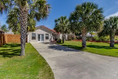 a house with palm trees in front of a driveway at Gulf View Home - Private Pool! in Panama City Beach