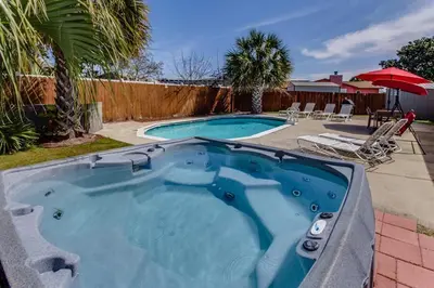 a large plunge pool in a yard with chairs and an umbrella at Gulf View Home - Private Pool! in Panama City Beach