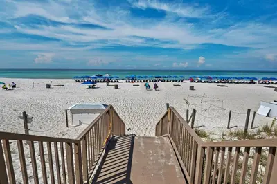 a stairway leading to a beach with people and umbrellas at Boardwalk 805 in Panama City Beach