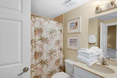a bathroom with a shower curtain with a toilet and a sink at Boardwalk 805 in Panama City Beach