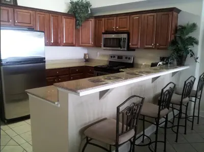 a kitchen with wooden cabinets and a counter with bar stools at Tropic Winds Condo in Panama City Beach