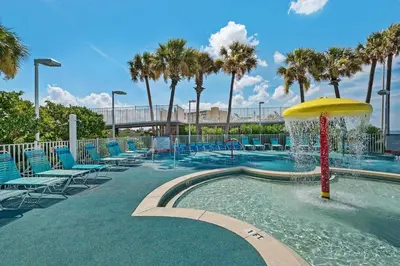 a swimming pool with chairs and a water fountain at Boardwalk 1405 in Panama City Beach