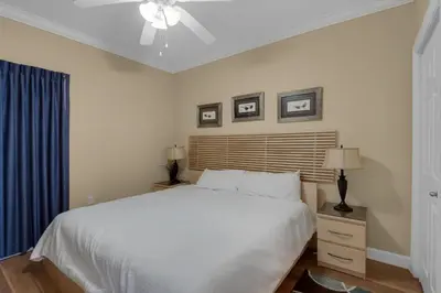 a bedroom with a white bed and a ceiling fan at Boardwalk 1405 in Panama City Beach