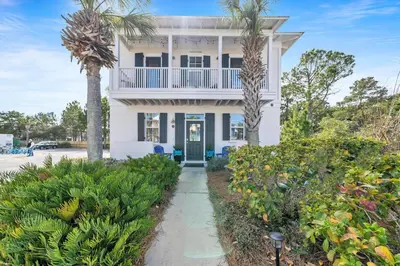 a white house with palm trees in front of it at Four Fish Bungalow 155 in Santa Rosa Beach