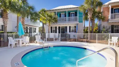 a swimming pool in front of a house with palm trees at Four Fish Bungalow 155 in Santa Rosa Beach