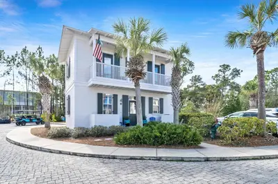 a white house with palm trees in front of it at Four Fish Bungalow 155 in Santa Rosa Beach