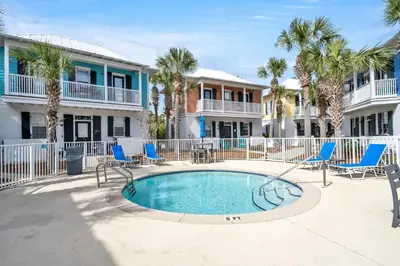 a pool with chairs and palm trees in front of condos at Four Fish Bungalow 155 in Santa Rosa Beach