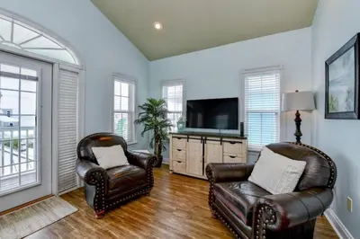 a living room with two chairs and a television at Sun Of A Beach - Beautiful Home Next To Pier Park - Swimming Pool! in Panama City Beach