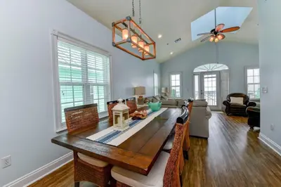 a dining room with a table and a living room at Sun Of A Beach - Beautiful Home Next To Pier Park - Swimming Pool! in Panama City Beach