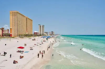a group of people on a beach near the ocean at Sun Of A Beach - Beautiful Home Next To Pier Park - Swimming Pool! in Panama City Beach