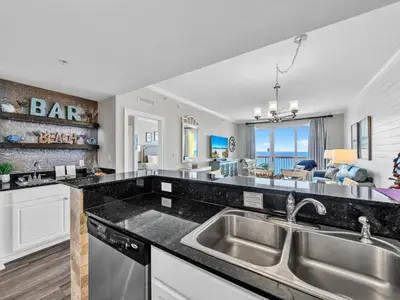 a kitchen with a sink and a living room at Calypso 2-1902 West in Panama City Beach