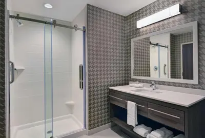 a bathroom with a shower and a sink and a mirror at Home2 Suites By Hilton Panama City Beach, Fl in Panama City Beach