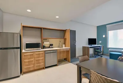 a kitchen with a stainless steel refrigerator and a table at Home2 Suites By Hilton Panama City Beach, Fl in Panama City Beach