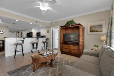 a living room with a couch and a table and a kitchen at Treasure Island 0210 in Panama City Beach