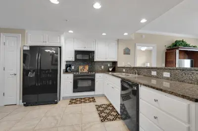 a kitchen with white cabinets and a black refrigerator at Treasure Island 0210 in Panama City Beach