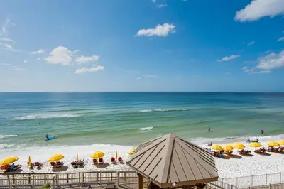 a beach with chairs and umbrellas and the ocean at Treasure Island 0305 in Panama City Beach