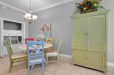 a dining room with a table and chairs and a cabinet at Treasure Island 0305 in Panama City Beach