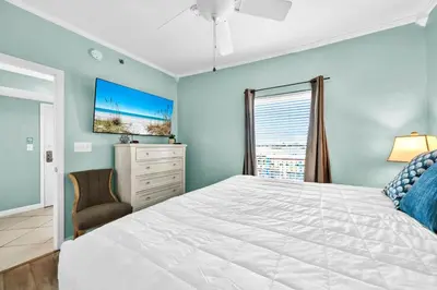 a bedroom with a bed and a dresser and a window at Splash 303E in Panama City Beach