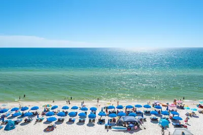 a beach with blue umbrellas and people on the beach at Splash 303E in Panama City Beach