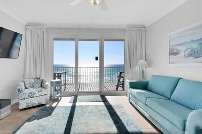 a living room with a blue couch and a balcony at Grandview East 304 in Panama City Beach
