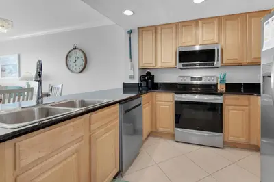 a kitchen with wooden cabinets and stainless steel appliances at Grandview East 304 in Panama City Beach