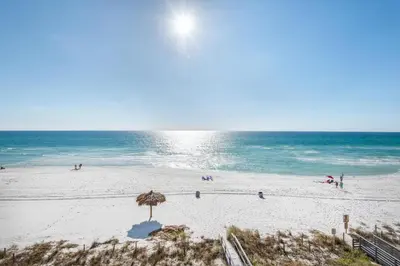a beach with an umbrella and people on the beach at Grandview East 304 in Panama City Beach