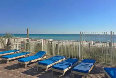a row of blue chaise lounges next to the beach at Grandview East 304 in Panama City Beach