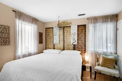 a bedroom with a white bed and a chair at Sandcastle Villas #24 in Panama City Beach