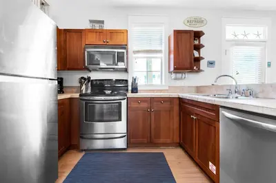 a kitchen with wooden cabinets and stainless steel appliances at Seagrove Bungalow 153 in Santa Rosa Beach