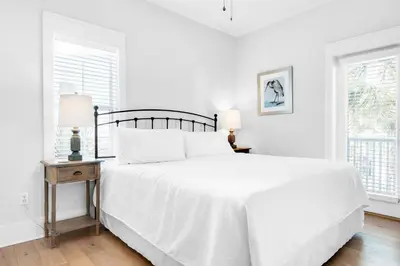 a white bedroom with a bed and two windows at Seagrove Bungalow 153 in Santa Rosa Beach