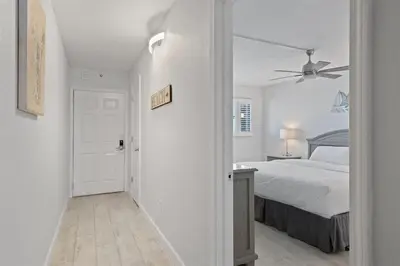 a white bedroom with a bed and a ceiling fan at The Summit 615 in Panama City Beach