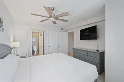 a white bedroom with a bed and a ceiling fan at The Summit 615 in Panama City Beach