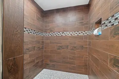 a bathroom with a shower with wooden walls at 5218 Beach Dr A in Panama City Beach