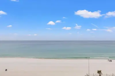 a group of people walking on a beach at The Summit 701 in Panama City Beach