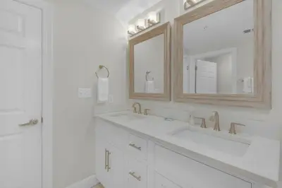 a white bathroom with two sinks and a mirror at Brightly Furnished Beachfront Condominium by Brightwild in Panama City Beach
