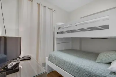 a bedroom with a bunk bed and a television at Brightly Furnished Beachfront Condominium by Brightwild in Panama City Beach