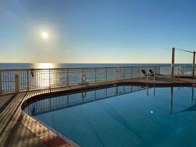 a swimming pool on the beach with the ocean in the background at Brightly Furnished Beachfront Condominium by Brightwild in Panama City Beach