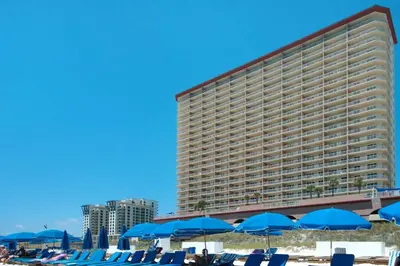a large hotel with blue beach chairs and umbrellas at Brightly Furnished Beachfront Condominium by Brightwild in Panama City Beach