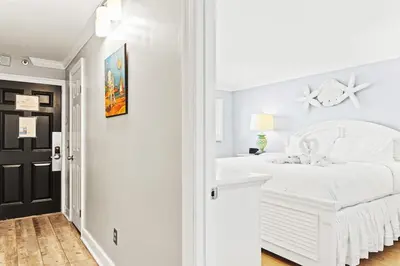 a white bedroom with a white bed and a black door at The Summit 1121 in Panama City Beach