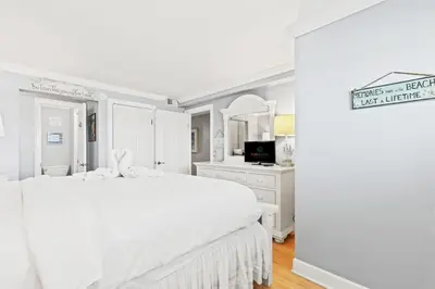 a white bedroom with a large bed and a desk at The Summit 1121 in Panama City Beach