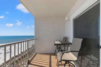 a balcony with two chairs and a table and the beach at The Summit 1121 in Panama City Beach